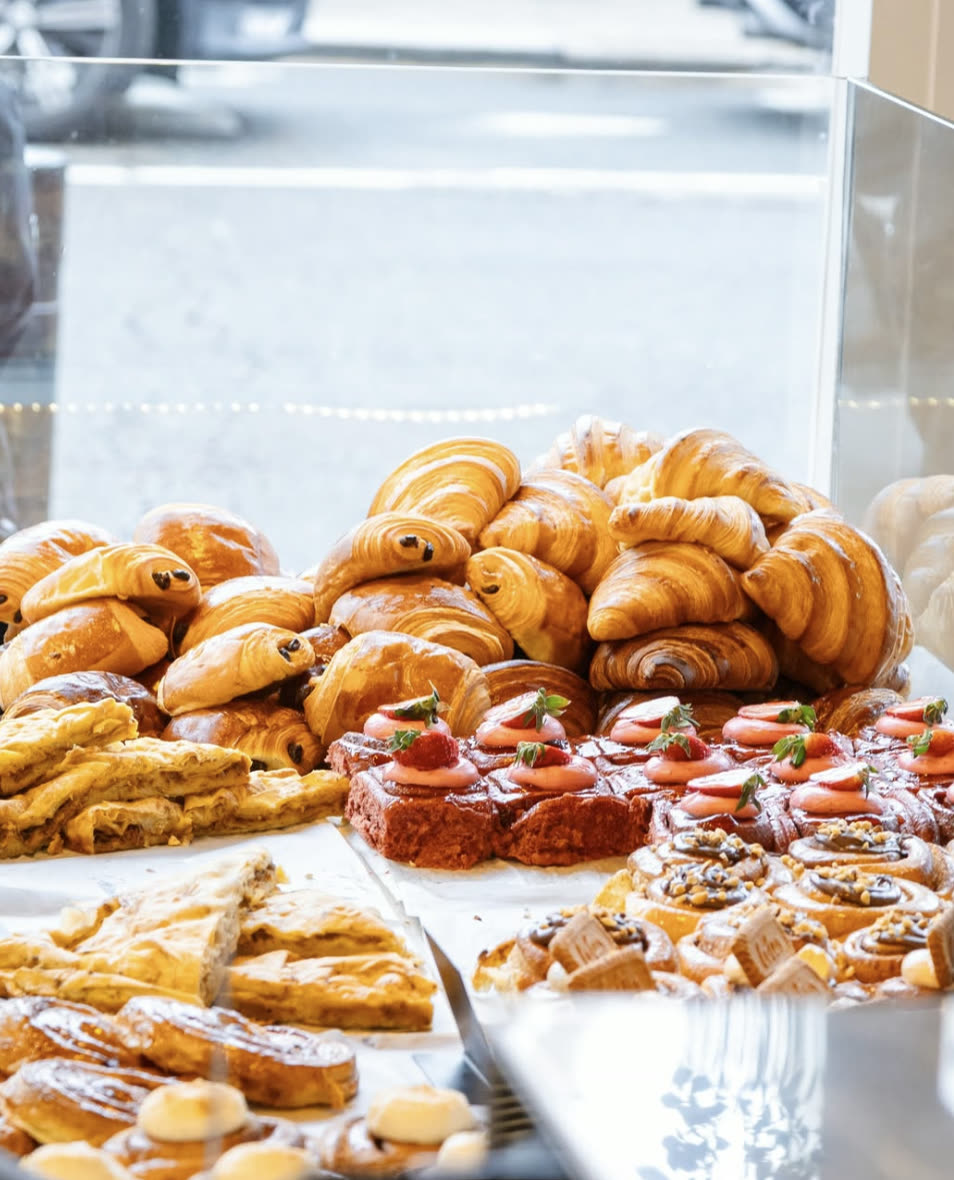 Counter display piled with croissants, pains au chocolat and strawberry tarts.